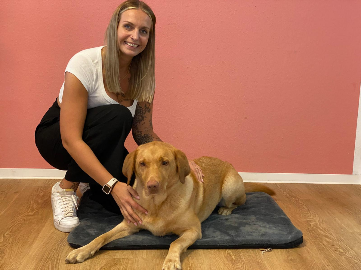 Tierphysiotherapeutin Denise neben der Manuly Hundematte mit einem Hund